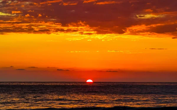 Beautiful stunning colorful and golden sunset in yellow orange red on beach and big wave panorama in tropical nature in Zicatela Puerto Escondido Oaxaca Mexico.