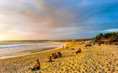 İnsanlar, Zicatela Puerto Escondido Oaxaca Mexico 'daki tropikal doğada sarı turuncu ve altın rengi günbatımını izliyorlar..