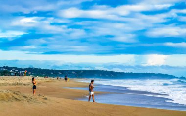 Palmiye ağaçları, şemsiyeler ve güneş şemsiyeleri Zicatela Puerto Escondido Oaxaca Meksika 'daki tropik Meksika plajındaki sahil tatil beldesi otelinde..