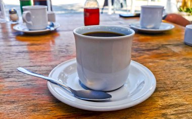 Quintana Roo Mexico 'daki Holbox Adası' ndaki restoranda bir fincan çay ve kaşık ile bir fincan americano kahvesi..