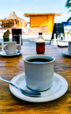 Quintana Roo Mexico 'daki Holbox Adası' ndaki restoranda bir fincan çay ve kaşık ile bir fincan americano kahvesi..