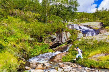 İnsanoğlu Vang i Valdres, Innlandet, Norveç 'teki küçük bir şelalenin akan suyundan atlıyor..