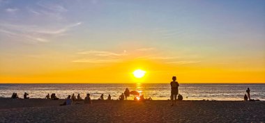 İnsanlar, Zicatela Puerto Escondido Oaxaca Mexico 'daki tropikal doğada sarı turuncu ve altın rengi günbatımını izliyorlar..