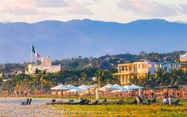 Puerto Escondido Oaxaca Meksika 02. Aralık 2022 'de insanlar Zicatela Puerto Escondido Oaxaca Meksika' daki tropikal doğada sarı turuncu ve altın rengi günbatımını ve büyük dalga panoramasını izliyorlar..