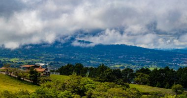 Orman ağaçları, bulutlar ve Orta Amerika 'da San Jose ve Heredia Kosta Rika' nın doğası olan güzel dağ manzarası ve şehir manzarası..