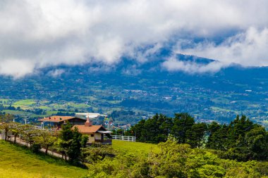 Orman ağaçları, bulutlar ve Orta Amerika 'da San Jose ve Heredia Kosta Rika' nın doğası olan güzel dağ manzarası ve şehir manzarası..