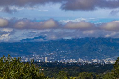 Orman ağaçları, bulutlar ve Orta Amerika 'da San Jose ve Heredia Kosta Rika' nın doğası olan güzel dağ manzarası ve şehir manzarası..