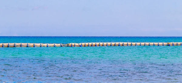 Beautiful blue and turquoise water waves ocean and yellow red orange buoy and ropes in the water of Playa del Carmen in Quintana Roo Mexico.