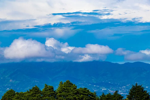 Orman ağaçları, bulutlar ve Orta Amerika 'da San Jose ve Heredia Kosta Rika' nın doğası olan güzel dağ manzarası ve şehir manzarası..