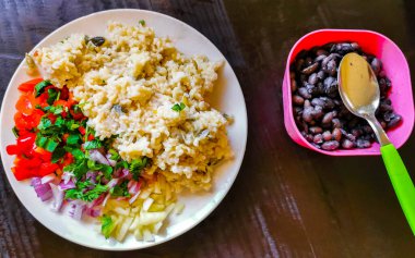 Vegetable dish soup with beans greens rice noodles onions tomato and garlic on a white plate bowl with fork or spoon in Mexico.