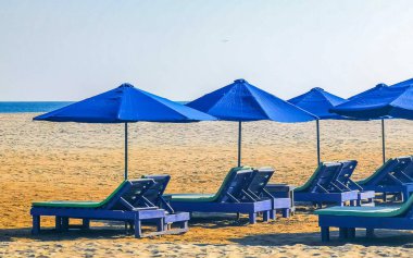 Palmiye ağaçları, şemsiyeler ve güneş şemsiyeleri Zicatela Puerto Escondido Oaxaca Meksika 'daki tropik Meksika plajındaki sahil tatil beldesi otelinde..