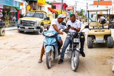 Two men on motorcycles look into cell phoneon Isla Holbox island in Quintana Roo Mexico.