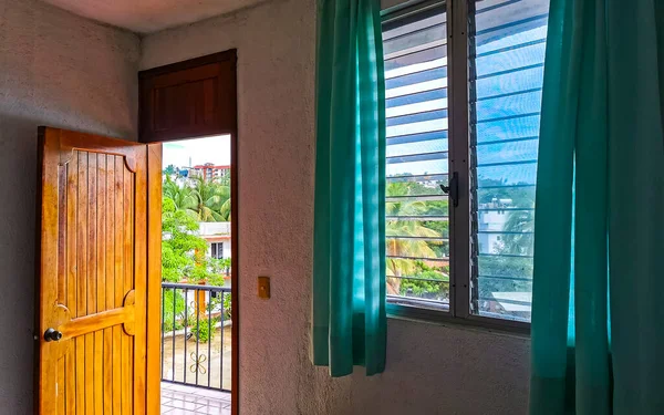 Simple small apartment hotel room with bed table toilet TV and refrigerator in Zicatela Puerto Escondido Oaxaca Mexico.