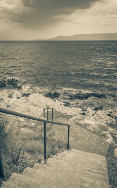 Novi Vinodolski Hırvatistan 'daki cennet turkuaz plajına ve gezinti güvertesine merdivenler.