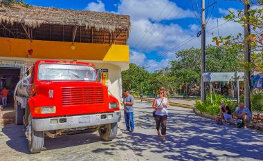 Tulum Mexico 09. March 2022 Typical colorful street road red water truck and cityscape with cars traffic palm tourism shops bars and restaurants of Tulum in Mexico.