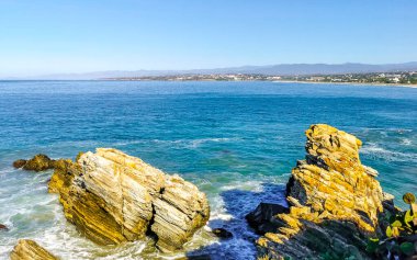 Beautiful rocks cliffs stones and boulders and huge big surfer waves on the beach in La Punta Zicatela Puerto Escondido Oaxaca Mexico.