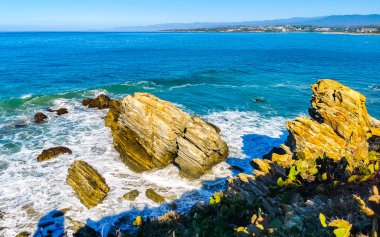 Beautiful rocks cliffs stones and boulders and huge big surfer waves on the beach in La Punta Zicatela Puerto Escondido Oaxaca Mexico.
