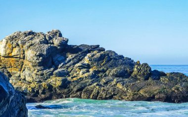 Beautiful rocks cliffs stones and boulders and huge big surfer waves on the beach in La Punta Zicatela Puerto Escondido Oaxaca Mexico.