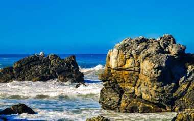 Beautiful rocks cliffs stones and boulders and huge big surfer waves on the beach in La Punta Zicatela Puerto Escondido Oaxaca Mexico.