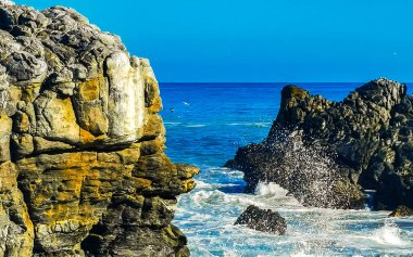 Beautiful rocks cliffs stones and boulders and huge big surfer waves on the beach in La Punta Zicatela Puerto Escondido Oaxaca Mexico.