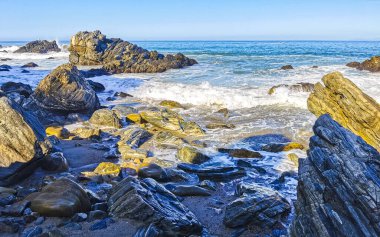 Beautiful rocks cliffs stones and boulders and huge big surfer waves on the beach in La Punta Zicatela Puerto Escondido Oaxaca Mexico.