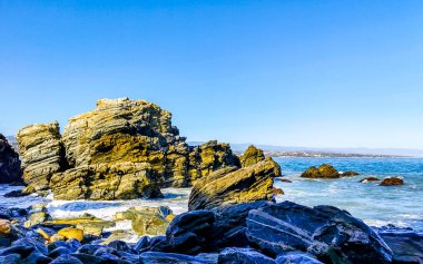 Beautiful rocks cliffs stones and boulders and huge big surfer waves on the beach in La Punta Zicatela Puerto Escondido Oaxaca Mexico.