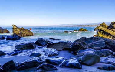 Beautiful rocks cliffs stones and boulders and huge big surfer waves on the beach in La Punta Zicatela Puerto Escondido Oaxaca Mexico.