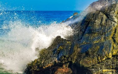 Beautiful rocks cliffs stones and boulders and huge big surfer waves on the beach in La Punta Zicatela Puerto Escondido Oaxaca Mexico.