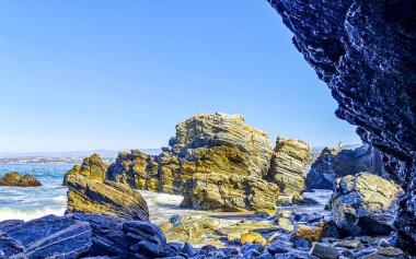 Beautiful rocks cliffs stones and boulders and huge big surfer waves on the beach in La Punta Zicatela Puerto Escondido Oaxaca Mexico.