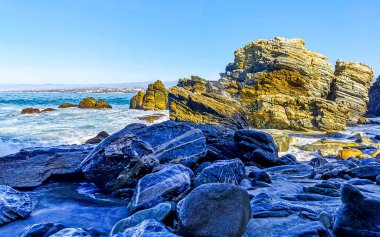 Beautiful rocks cliffs stones and boulders and huge big surfer waves on the beach in La Punta Zicatela Puerto Escondido Oaxaca Mexico.