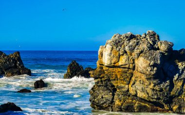 Beautiful rocks cliffs stones and boulders and huge big surfer waves on the beach in La Punta Zicatela Puerto Escondido Oaxaca Mexico.