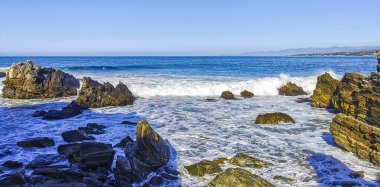Beautiful rocks cliffs stones and boulders and huge big surfer waves on the beach in La Punta Zicatela Puerto Escondido Oaxaca Mexico.