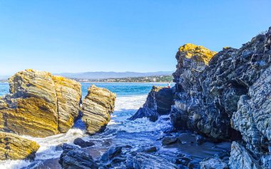 Beautiful rocks cliffs stones and boulders and huge big surfer waves on the beach in La Punta Zicatela Puerto Escondido Oaxaca Mexico.