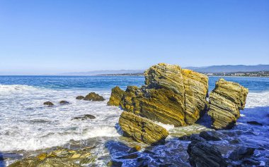 Beautiful rocks cliffs stones and boulders and huge big surfer waves on the beach in La Punta Zicatela Puerto Escondido Oaxaca Mexico.