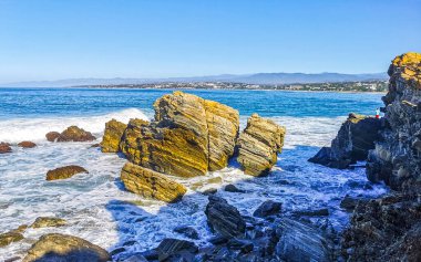 Beautiful rocks cliffs stones and boulders and huge big surfer waves on the beach in La Punta Zicatela Puerto Escondido Oaxaca Mexico.