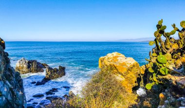Beautiful rocks cliffs stones and boulders and huge big surfer waves on the beach in La Punta Zicatela Puerto Escondido Oaxaca Mexico.