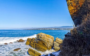 Beautiful rocks cliffs stones and boulders and huge big surfer waves on the beach in La Punta Zicatela Puerto Escondido Oaxaca Mexico.