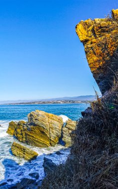 Beautiful rocks cliffs stones and boulders and huge big surfer waves on the beach in La Punta Zicatela Puerto Escondido Oaxaca Mexico.