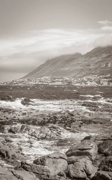 False Bay rough coast landscape with boulders waves and mountains with clouds in Glencairn Simons Town Cape Town Western Cape South Africa.