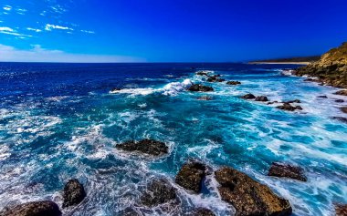 Beautiful rocks cliffs stones and boulders and huge big surfer waves and natural panorama view on the beach in Bacocho Puerto Escondido Oaxaca Mexico.