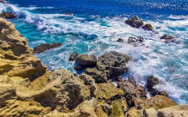 Beautiful rocks cliffs stones and boulders and huge big surfer waves and natural panorama view on the beach in Bacocho Puerto Escondido Oaxaca Mexico.
