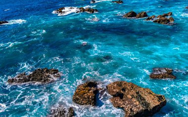 Beautiful rocks cliffs stones and boulders and huge big surfer waves and natural panorama view on the beach in Bacocho Puerto Escondido Oaxaca Mexico.