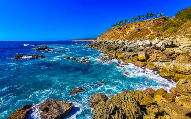 Beautiful rocks cliffs stones and boulders and huge big surfer waves and natural panorama view on the beach in Bacocho Puerto Escondido Oaxaca Mexico.