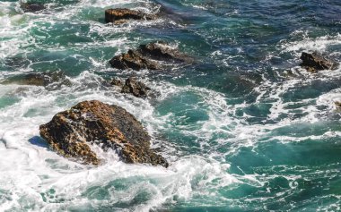 Beautiful rocks cliffs stones and boulders and huge big surfer waves and natural panorama view on the beach in Bacocho Puerto Escondido Oaxaca Mexico.