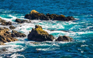 Beautiful rocks cliffs stones and boulders and huge big surfer waves and natural panorama view on the beach in Bacocho Puerto Escondido Oaxaca Mexico.