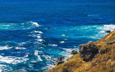 Beautiful rocks cliffs stones and boulders and huge big surfer waves and natural panorama view on the beach in Bacocho Puerto Escondido Oaxaca Mexico.