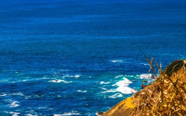 Beautiful rocks cliffs stones and boulders and huge big surfer waves and natural panorama view on the beach in Bacocho Puerto Escondido Oaxaca Mexico.