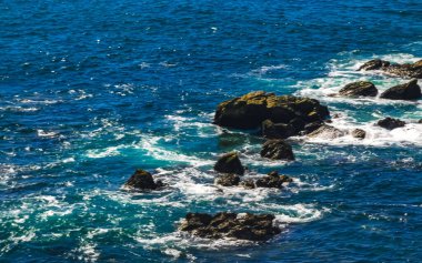 Beautiful rocks cliffs stones and boulders and huge big surfer waves and natural panorama view on the beach in Bacocho Puerto Escondido Oaxaca Mexico.