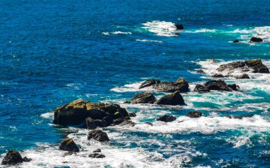 Beautiful rocks cliffs stones and boulders and huge big surfer waves and natural panorama view on the beach in Bacocho Puerto Escondido Oaxaca Mexico.