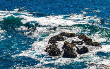 Beautiful rocks cliffs stones and boulders and huge big surfer waves and natural panorama view on the beach in Bacocho Puerto Escondido Oaxaca Mexico.